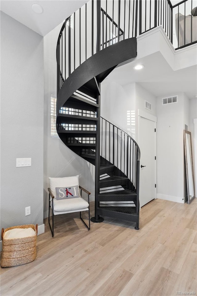 stairway with hardwood / wood-style flooring and a high ceiling