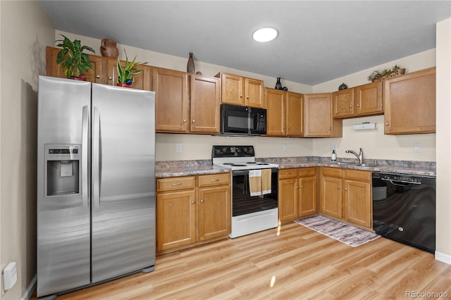 kitchen featuring black appliances, light hardwood / wood-style floors, and sink