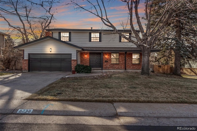 traditional-style home with a garage, driveway, a lawn, and brick siding