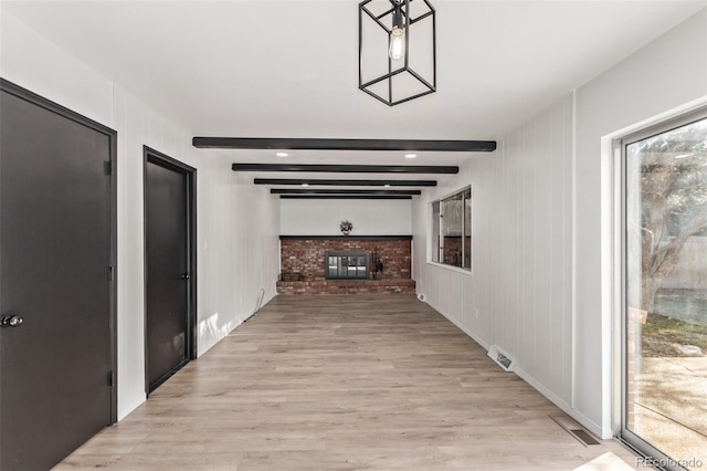 hall featuring light wood-type flooring, visible vents, and beam ceiling