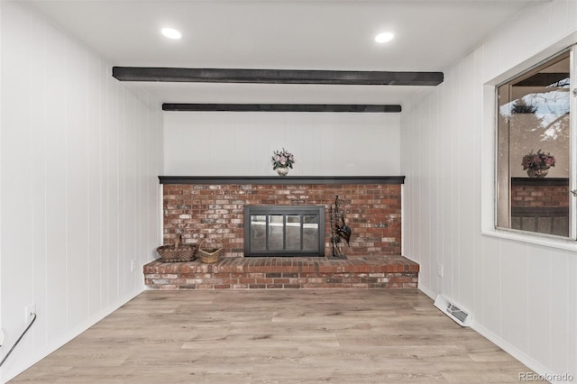 unfurnished living room featuring recessed lighting, visible vents, light wood-type flooring, a brick fireplace, and beamed ceiling