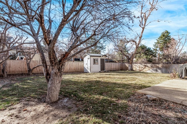 view of yard featuring a storage shed, a fenced backyard, and an outbuilding