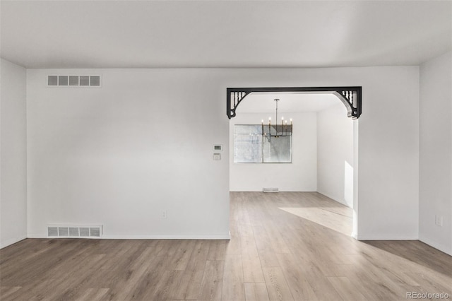 unfurnished dining area featuring wood finished floors, visible vents, and an inviting chandelier