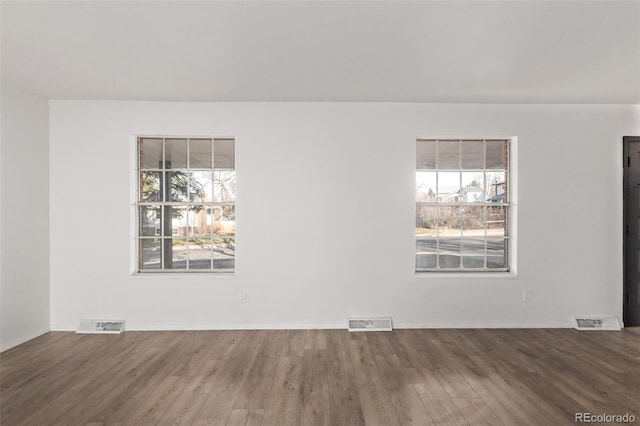 empty room with visible vents, baseboards, and wood finished floors