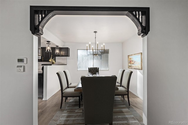 dining room featuring baseboards, dark wood-style flooring, arched walkways, and an inviting chandelier