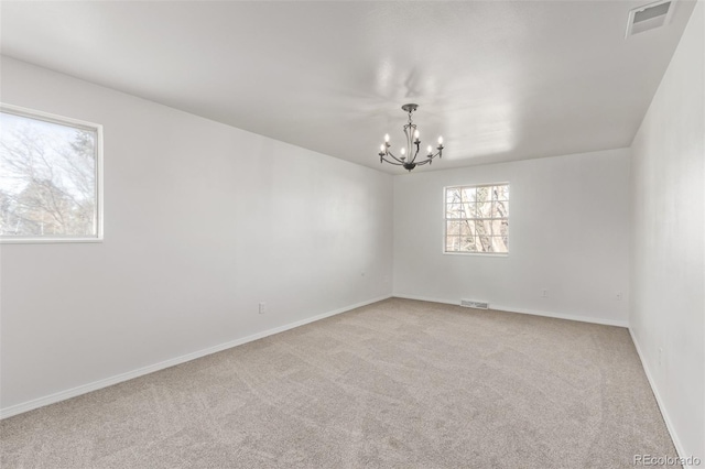 carpeted empty room with visible vents, baseboards, and an inviting chandelier