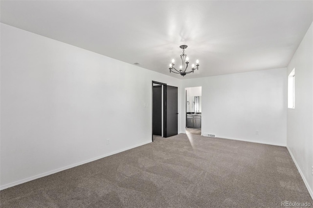 unfurnished room with carpet floors, visible vents, a notable chandelier, and baseboards