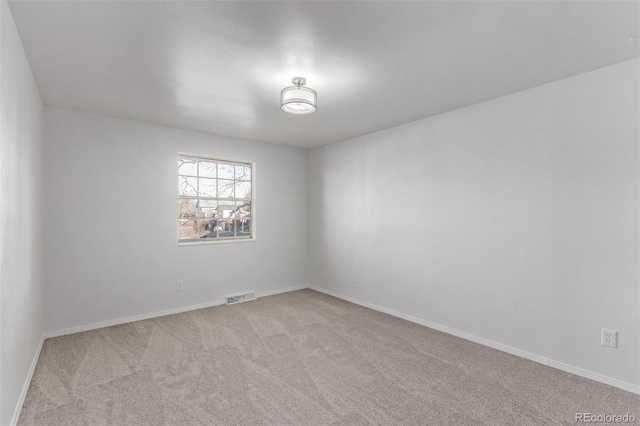 empty room with visible vents, light carpet, and baseboards