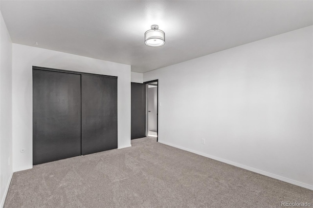 unfurnished bedroom featuring light carpet, a closet, and baseboards