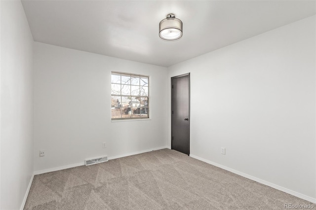 empty room with baseboards, visible vents, and light colored carpet