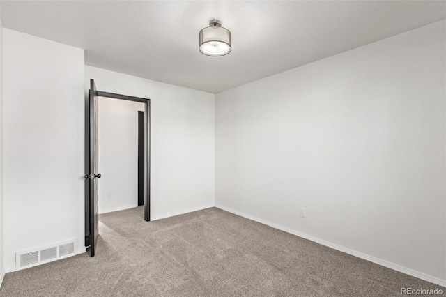 spare room featuring light carpet, visible vents, and baseboards