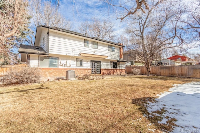 back of property featuring a yard, brick siding, fence, and central air condition unit