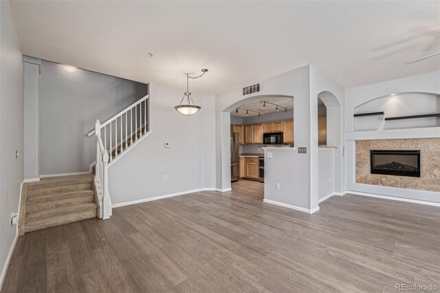 1535 S Florence Way Unit 410, Aurora, CO 80247 - unfurnished living room with wood finished floors, stairway, arched walkways, and a tile fireplace