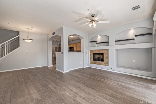 1535 S Florence Way Unit 410, Aurora, CO 80247 - unfurnished living room featuring ceiling fan, wood finished floors, stairway, and arched walkways