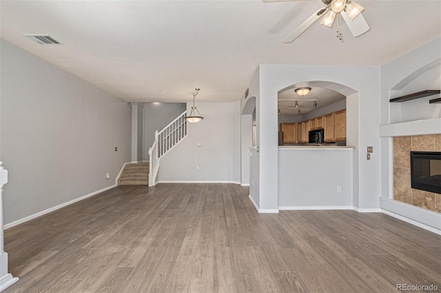1535 S Florence Way Unit 410, Aurora, CO 80247 - unfurnished living room with wood finished floors, stairway, ceiling fan, and a tiled fireplace