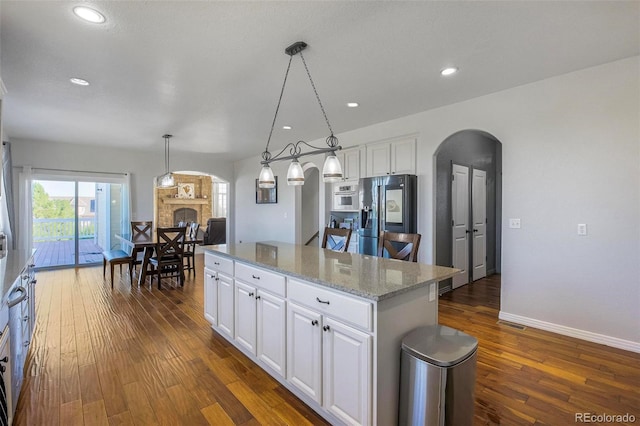 kitchen with decorative light fixtures, a kitchen island, stainless steel fridge with ice dispenser, and white cabinetry