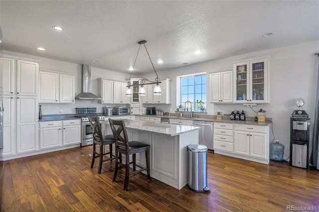 kitchen featuring wall chimney exhaust hood, stainless steel appliances, and white cabinets