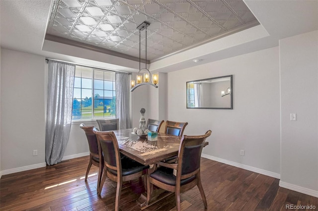 dining space featuring dark hardwood / wood-style flooring, a notable chandelier, and a tray ceiling