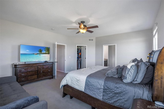 bedroom featuring a spacious closet, ceiling fan, a closet, ensuite bathroom, and light colored carpet