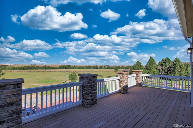 wooden terrace with a yard and a rural view