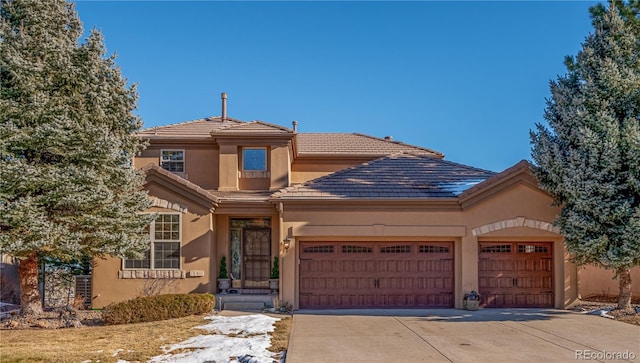 view of front facade featuring driveway, a tiled roof, an attached garage, and stucco siding