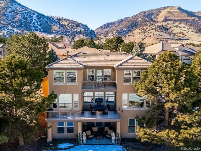 rear view of house featuring a mountain view, a patio, a balcony, and stucco siding