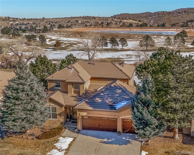 traditional-style home with a garage, driveway, a tile roof, and stucco siding