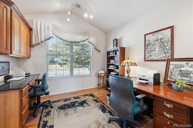 office featuring vaulted ceiling, baseboards, light wood finished floors, and built in study area