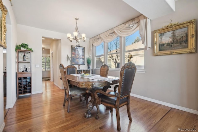 dining room featuring a notable chandelier, baseboards, and light wood-type flooring