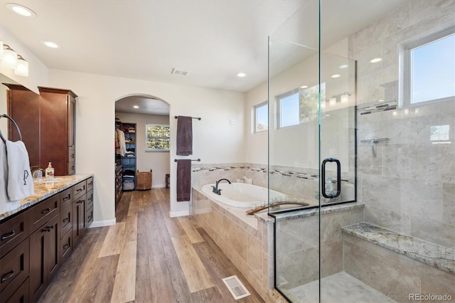 bathroom featuring plenty of natural light, wood finished floors, visible vents, and a stall shower