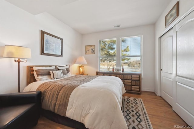 bedroom featuring visible vents, a closet, and wood finished floors