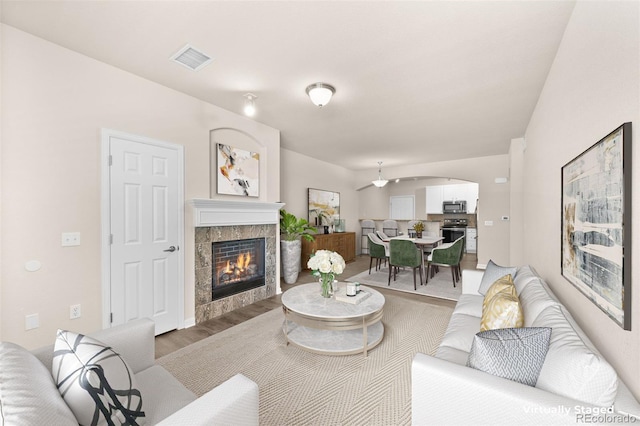 living area featuring light wood-style flooring, a fireplace, and arched walkways