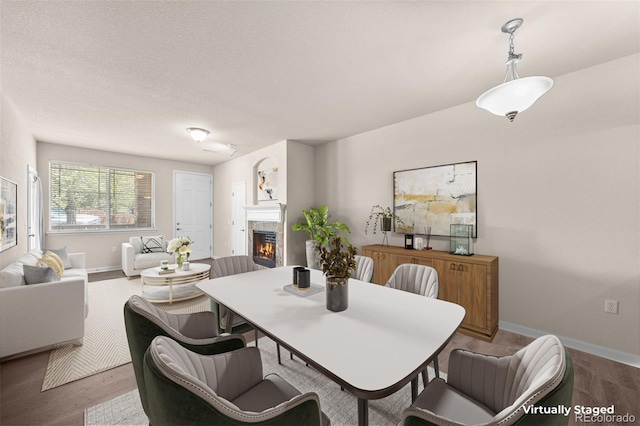 dining space featuring a tiled fireplace, wood finished floors, and baseboards