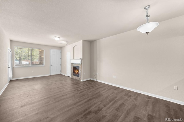 unfurnished living room featuring dark wood-type flooring, a fireplace, baseboards, and a textured ceiling