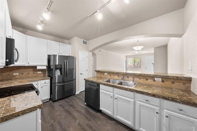 kitchen with stainless steel appliances, a sink, arched walkways, track lighting, and backsplash
