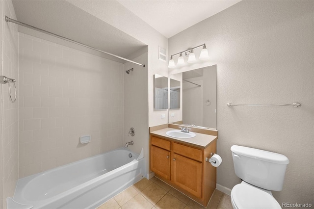 bathroom featuring tile patterned floors, bathtub / shower combination, toilet, vanity, and a textured wall