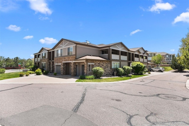 view of front of property featuring concrete driveway, stucco siding, a garage, and stone siding