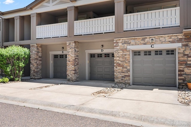 view of front of home featuring stone siding, an attached garage, and driveway