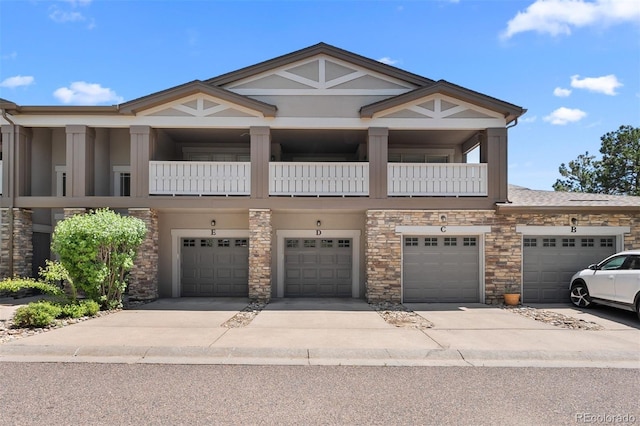 view of property with stone siding, an attached garage, and driveway