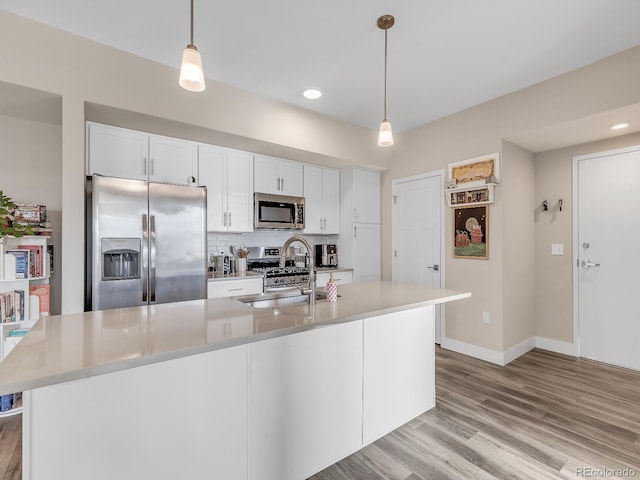 kitchen with white cabinetry, appliances with stainless steel finishes, sink, and a kitchen island with sink