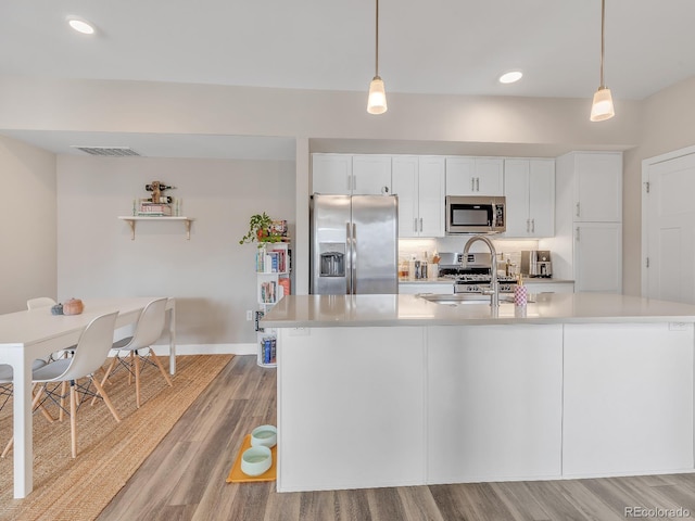 kitchen featuring white cabinetry, hanging light fixtures, light wood-type flooring, and appliances with stainless steel finishes