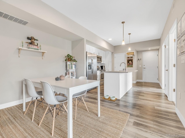 dining space with sink and light hardwood / wood-style flooring