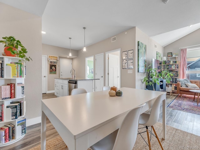 dining room featuring vaulted ceiling, sink, and light wood-type flooring