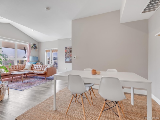 dining area with light hardwood / wood-style floors and vaulted ceiling