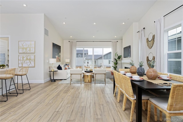 dining space with light wood-type flooring and lofted ceiling