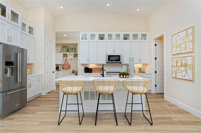 kitchen featuring appliances with stainless steel finishes, a center island with sink, and white cabinets