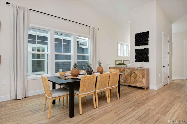 dining room with light hardwood / wood-style flooring and vaulted ceiling