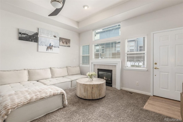 living room with carpet flooring, a tiled fireplace, and ceiling fan