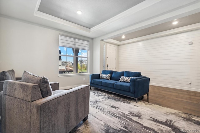 living room with hardwood / wood-style floors, a tray ceiling, ornamental molding, and wooden walls