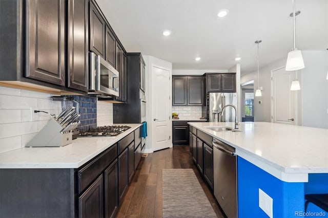 kitchen featuring appliances with stainless steel finishes, sink, backsplash, hanging light fixtures, and dark hardwood / wood-style floors